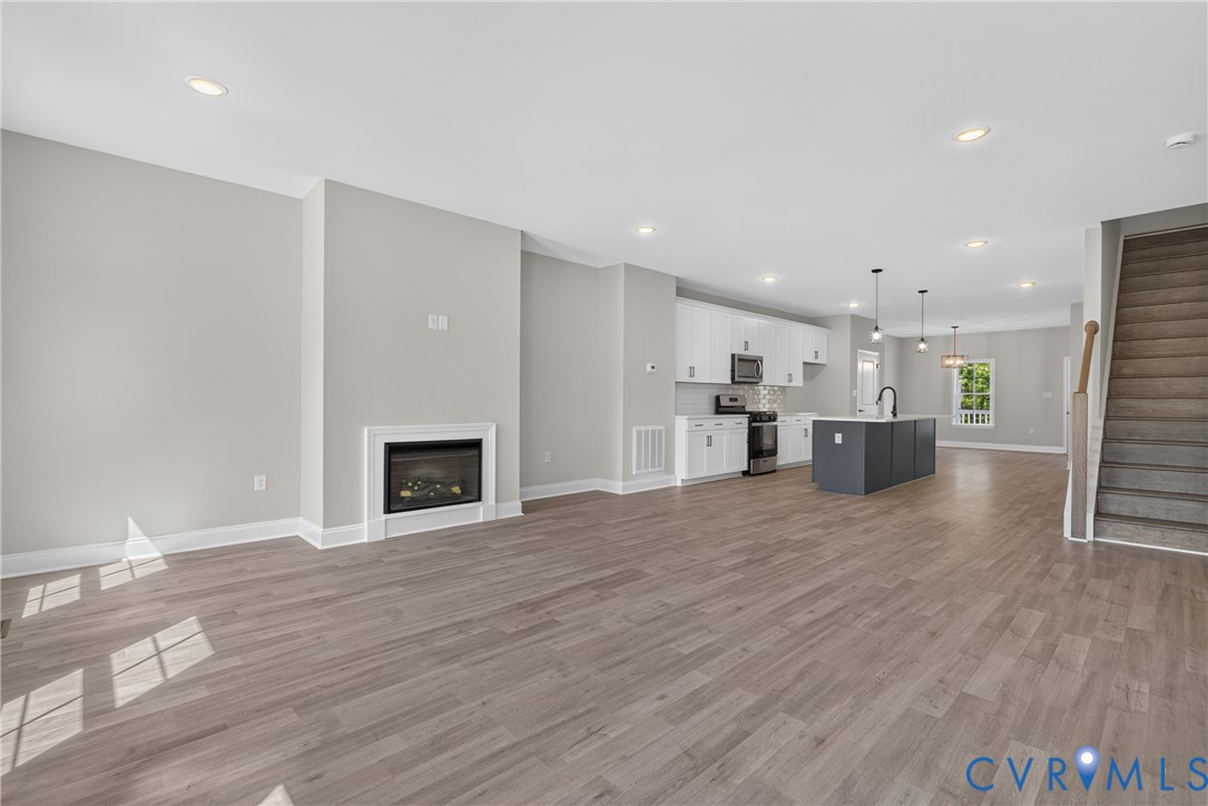 Open-concept living area featuring wood-finish flooring and a contemporary fireplace