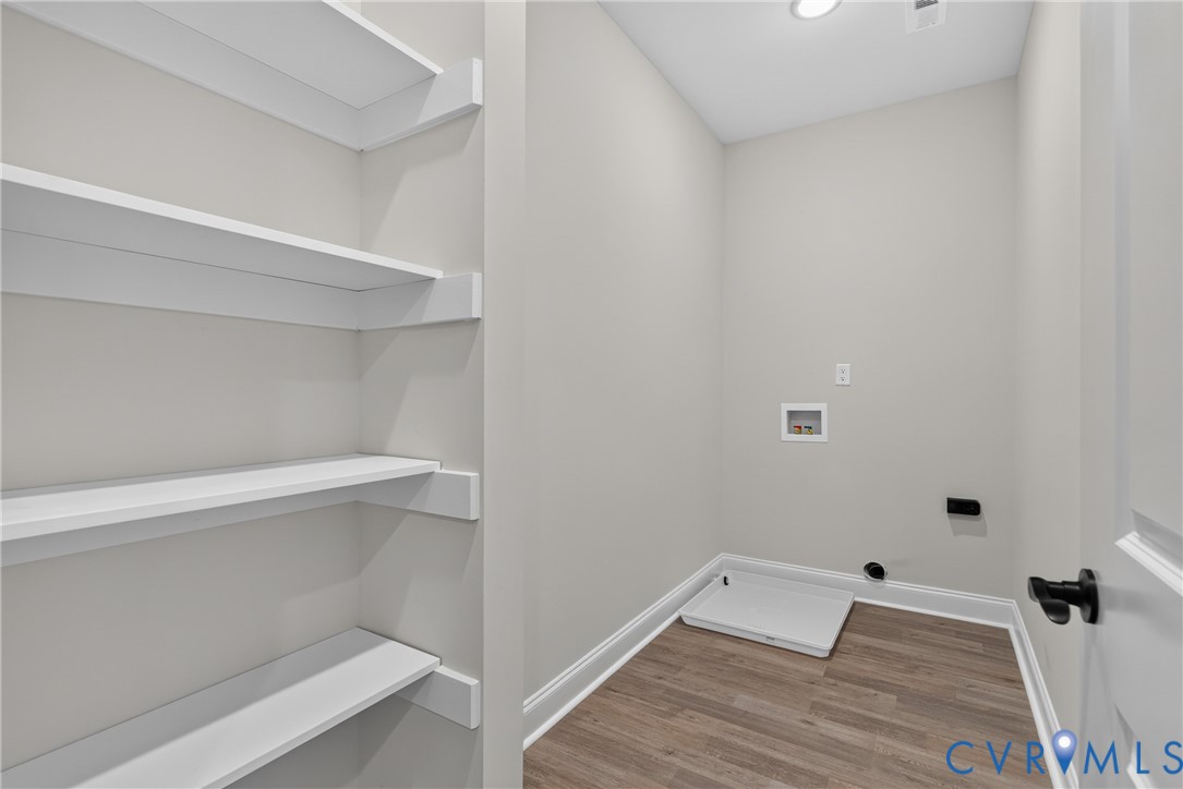 Room featuring white walls, wood-finish flooring, recessed lighting, and built-in shelving