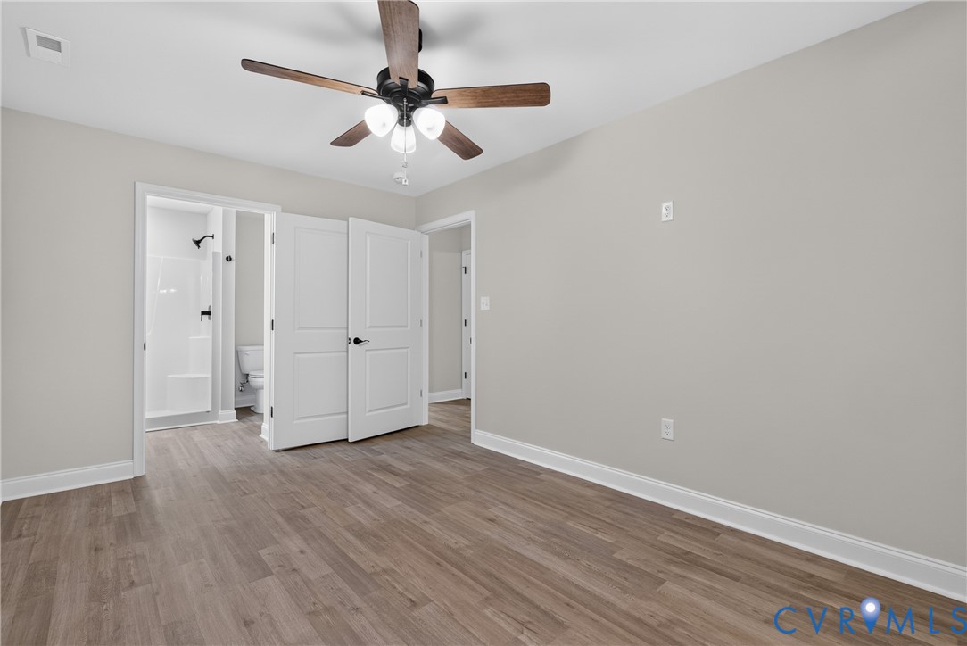 Wood-finish flooring throughout, light gray wall finishes, and a ceiling fan with integrated lighting Wood-finish flooring throughout, light gray wall finishes, and a ceiling fan with integrated lighting