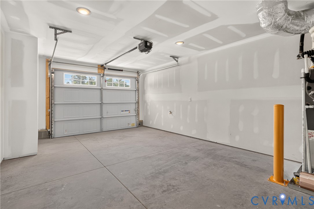 Concrete flooring, white walls, and a multi-panel garage door with upper window inserts