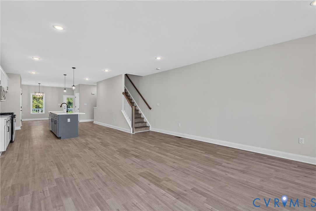 Expansive open-concept layout featuring wood-finish flooring, recessed lighting, and a contemporary kitchen island with a basin sink