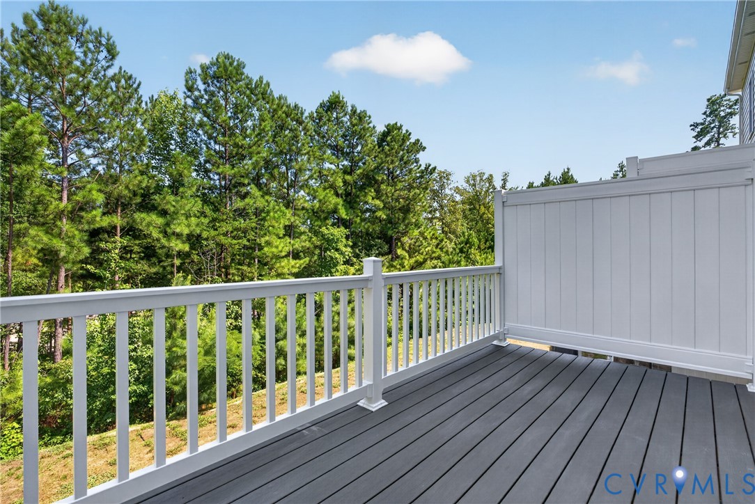 Outdoor deck featuring composite decking, white railing, and a privacy wall