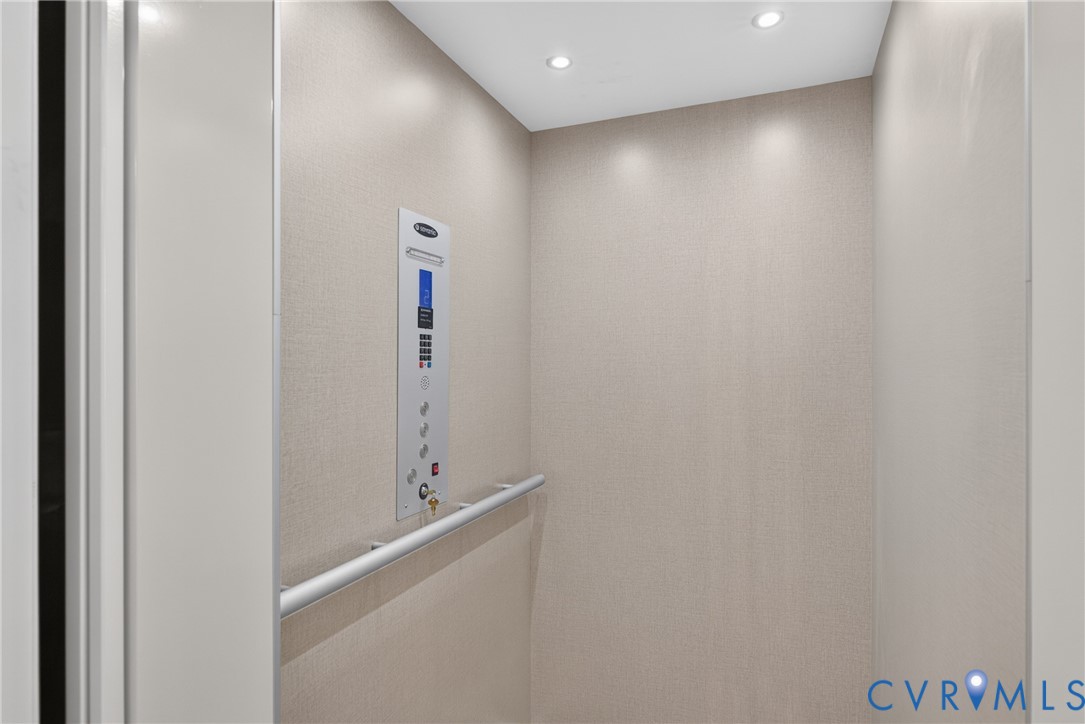 Residential elevator featuring a control panel and integrated grab bar