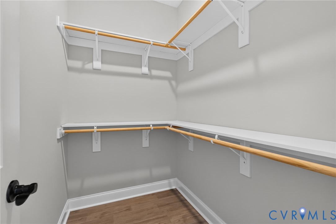 Built-in shelving and hanging rods with wood-finish flooring and white trim