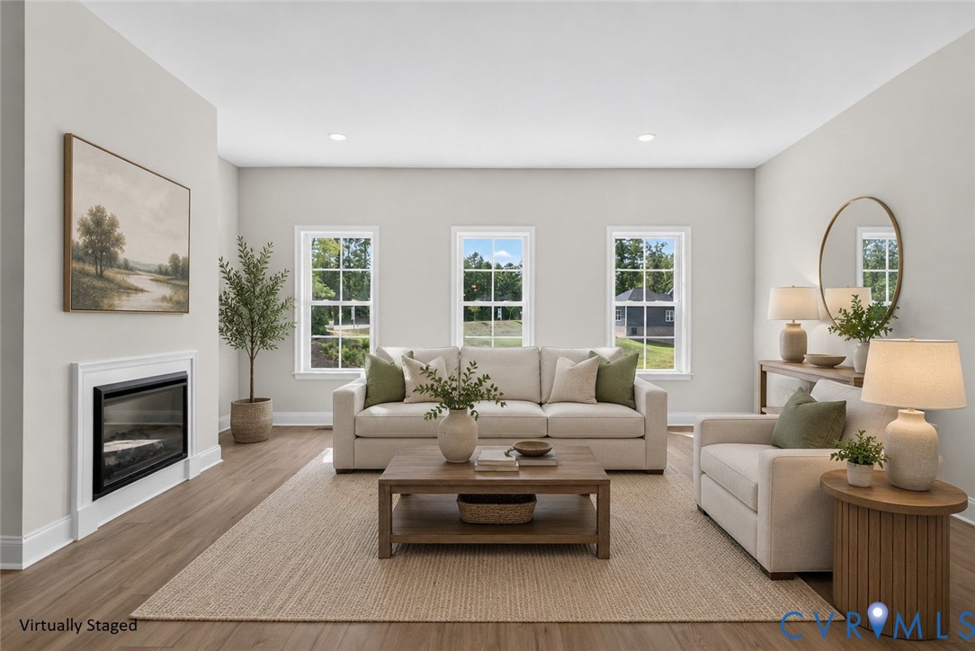 Recessed lighting, wood-finish flooring, three windows with white frames, and a built-in fireplace with white mantel