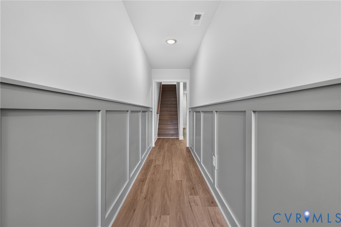 Hallway featuring wood-finish flooring, two-tone walls with wainscoting, and recessed lighting Hallway featuring wood-finish flooring, two-tone walls with wainscoting, and recessed lighting