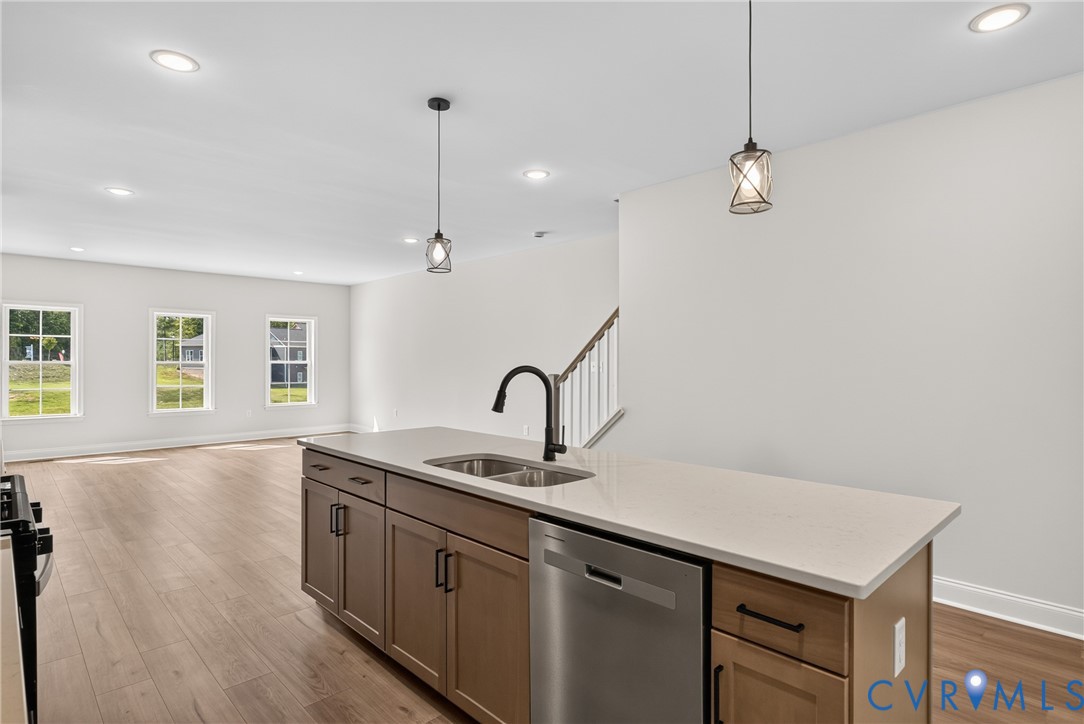 Kitchen island with a double basin sink, stainless steel dishwasher, and light-toned countertop