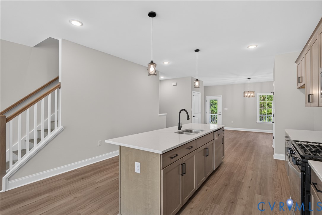 Open-concept kitchen and living area featuring a large center island with wood-finish cabinetry and white quartz countertop, black gooseneck faucet, and pendant lighting