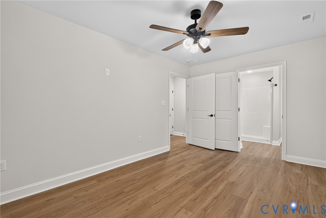 Wood-finish flooring, white trim, and a ceiling fan with integrated lighting Wood-finish flooring, white trim, and a ceiling fan with integrated lighting