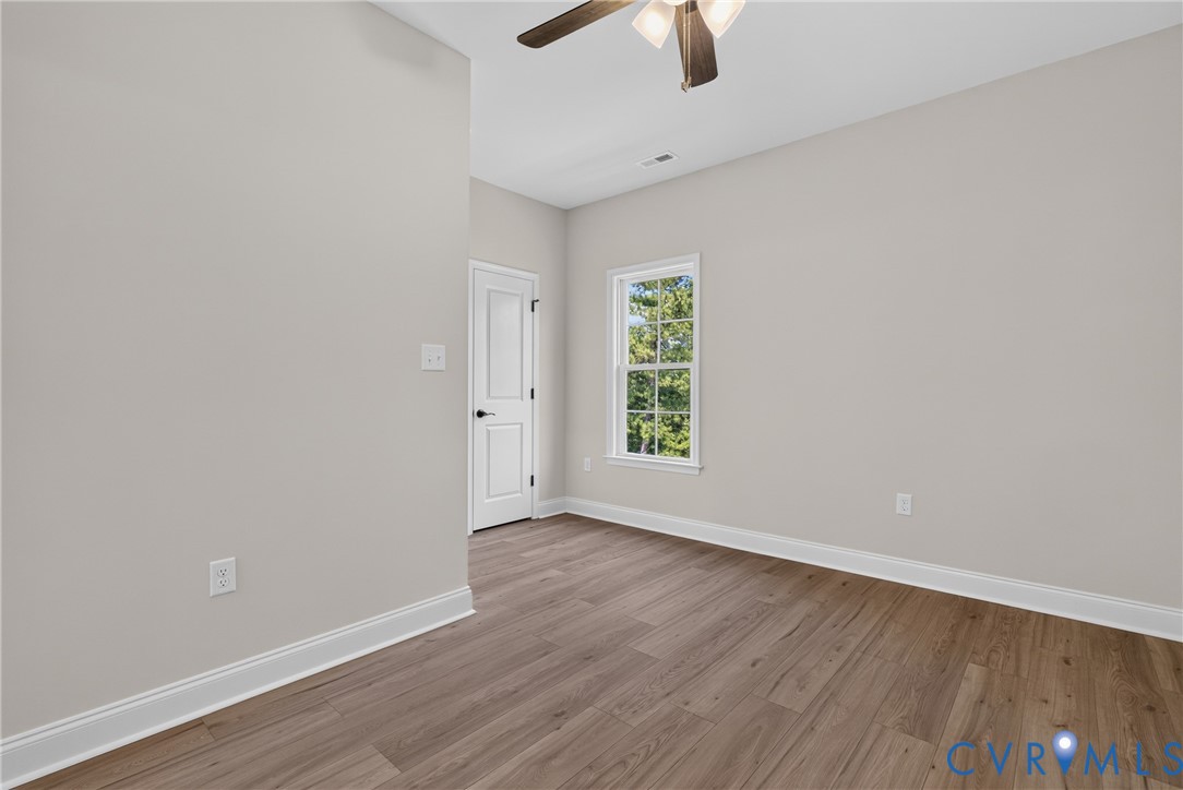 Wood-finish flooring with white trim, a double-panel door, and a single window