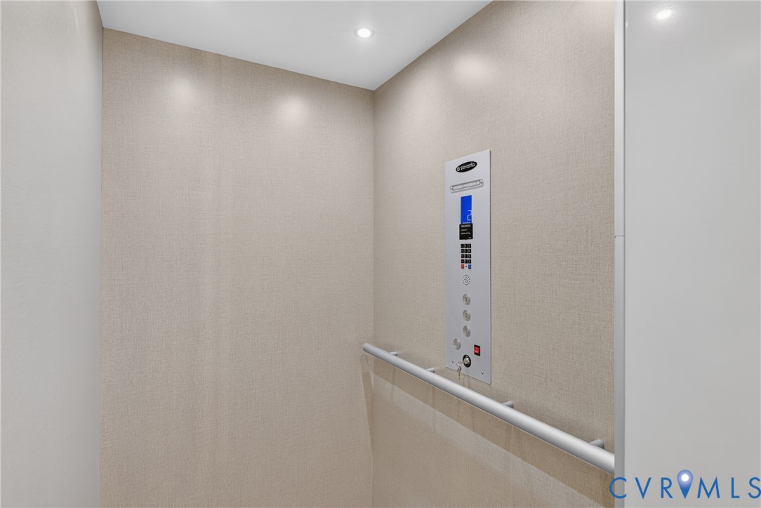 Integrated elevator featuring light-toned walls, recessed lighting, and a grab bar