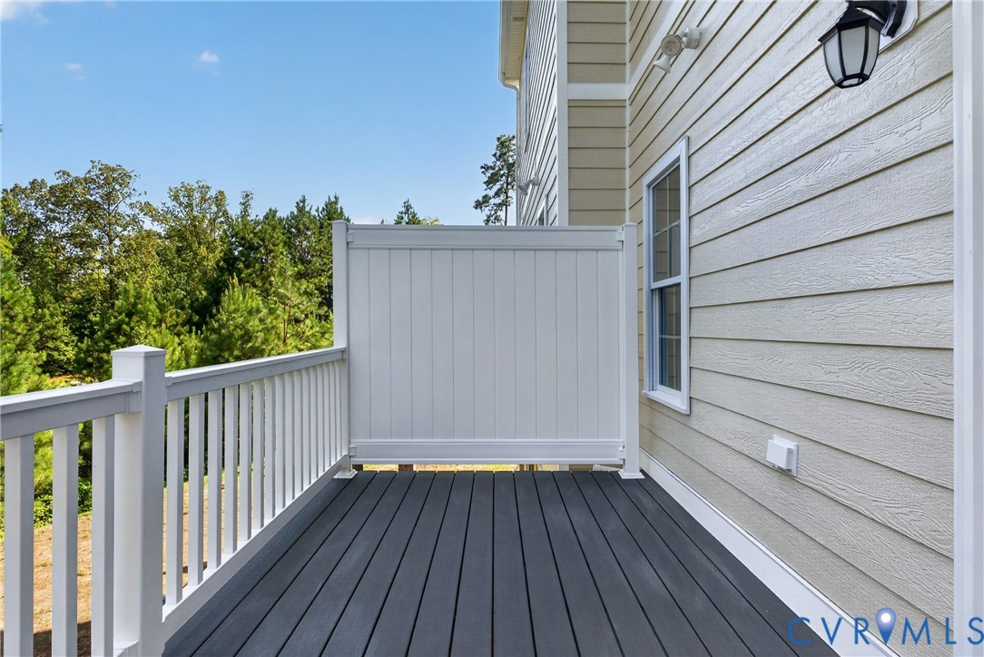 Exterior deck featuring dark composite decking, white railing, and a privacy panel