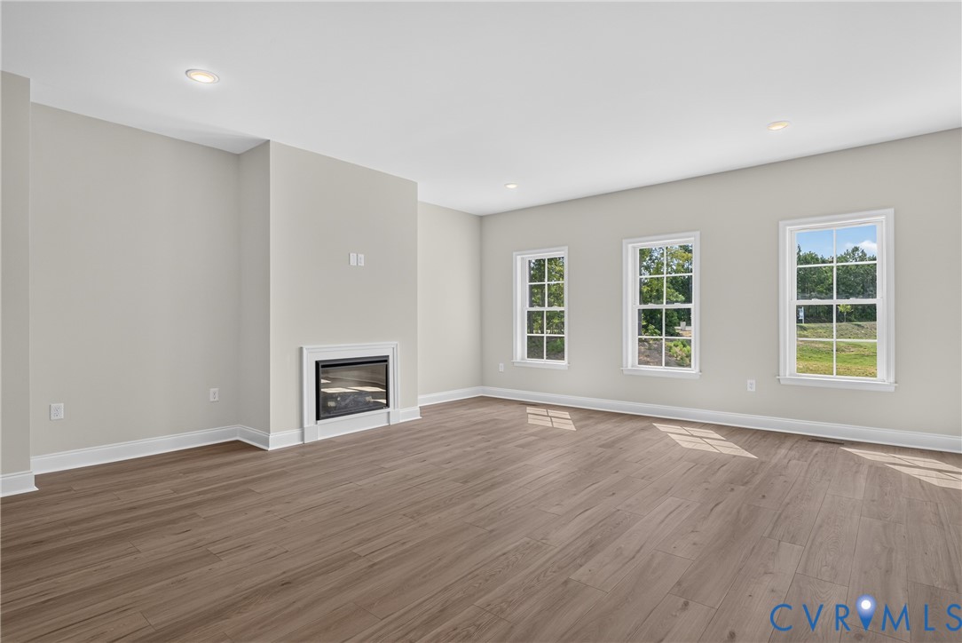 Recessed lighting, wood-finish flooring, and a built-in fireplace with a white surround