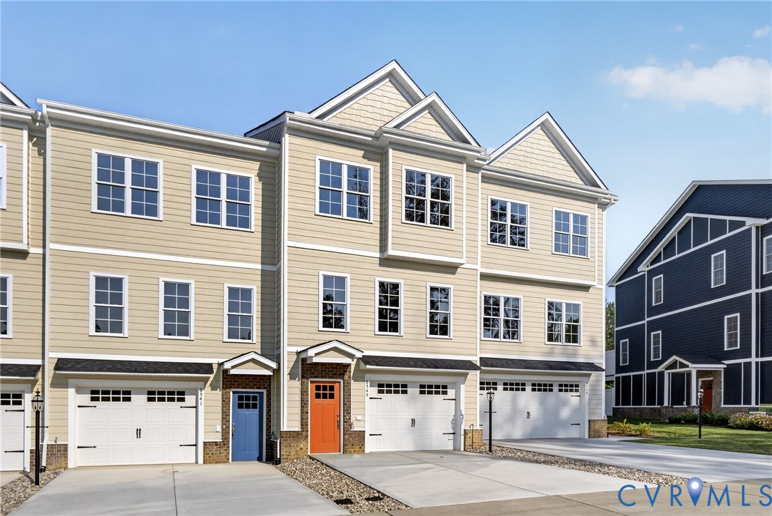 Multi-level townhouse exterior featuring light-colored siding, multiple windows, attached garages, and distinctive front entry doors