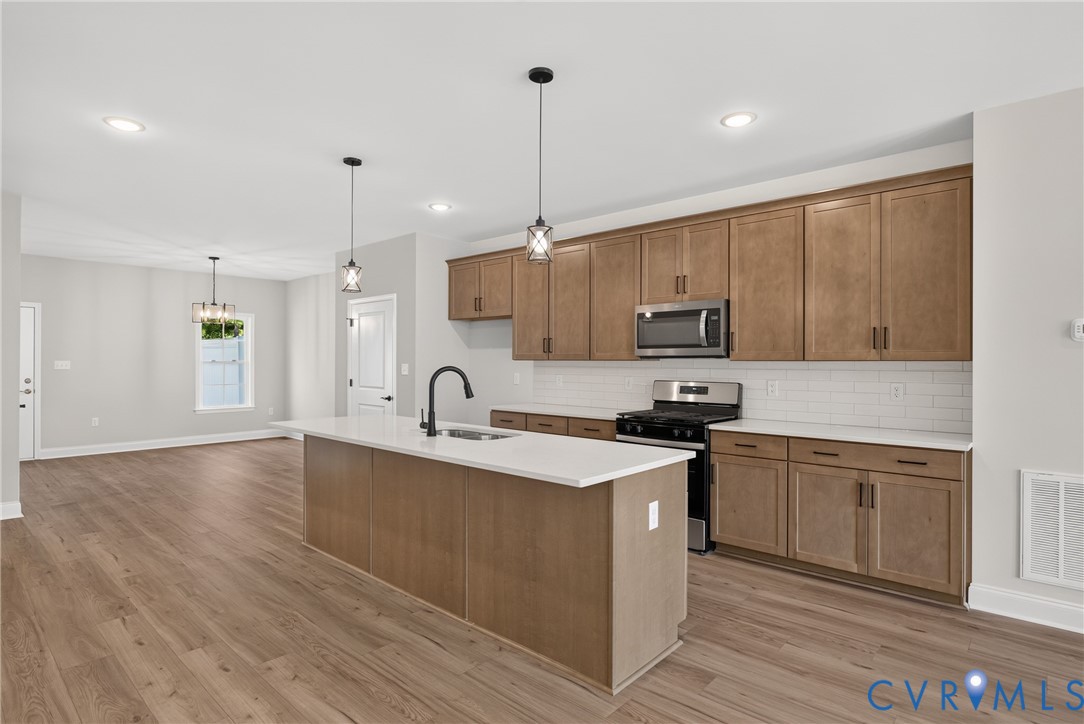 Kitchen featuring a central island with countertop, wood-finish flooring, stainless steel appliances, and wood cabinetry