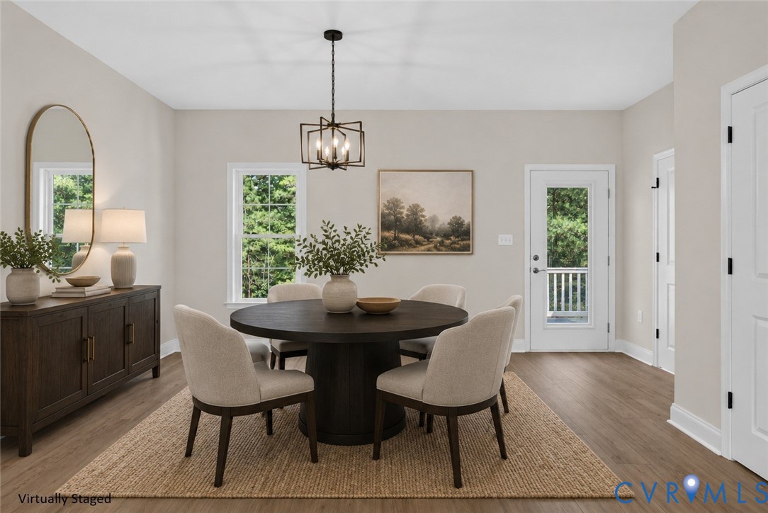 Expansive dining area featuring wood-finish flooring, a contemporary chandelier, multiple windows, and a glass-paneled door