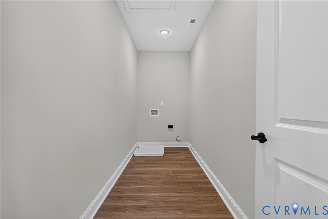 Dedicated laundry area featuring wood-finish flooring, light gray walls, and a recessed ceiling light