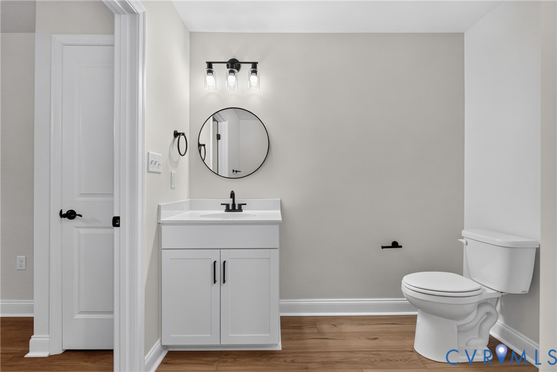 White vanity with matte black hardware, single white basin, white countertop, and dark wood-finish flooring White vanity with matte black hardware, single white basin, white countertop, and dark wood-finish flooring