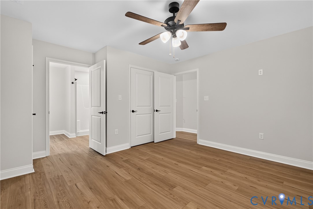 Wood-finish flooring, recessed lighting, ceiling fan with wood-tone blades, white paneled doors, and light gray wall finish Wood-finish flooring, recessed lighting, ceiling fan with wood-tone blades, white paneled doors, and light gray wall finish