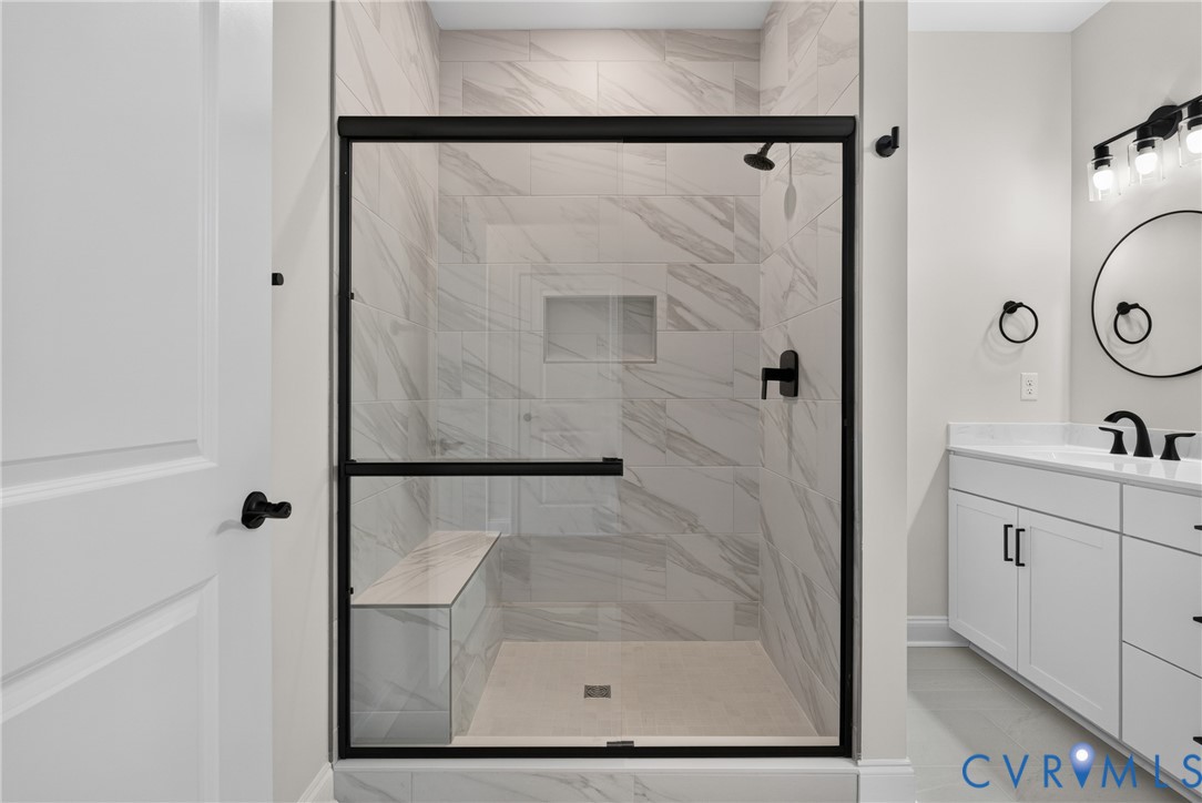 Walk-in shower with a built-in bench, tiled walls, and a recessed niche