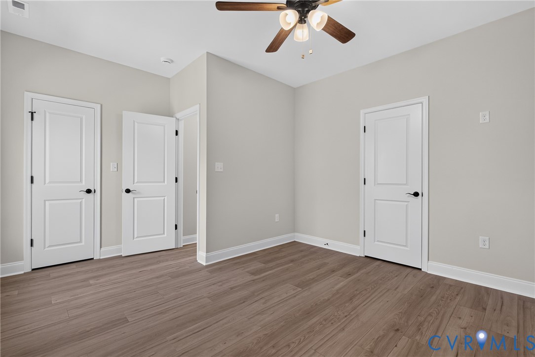 Wood-finish flooring, ceiling fan with integrated lighting, painted interior doors, and neutral wall tones