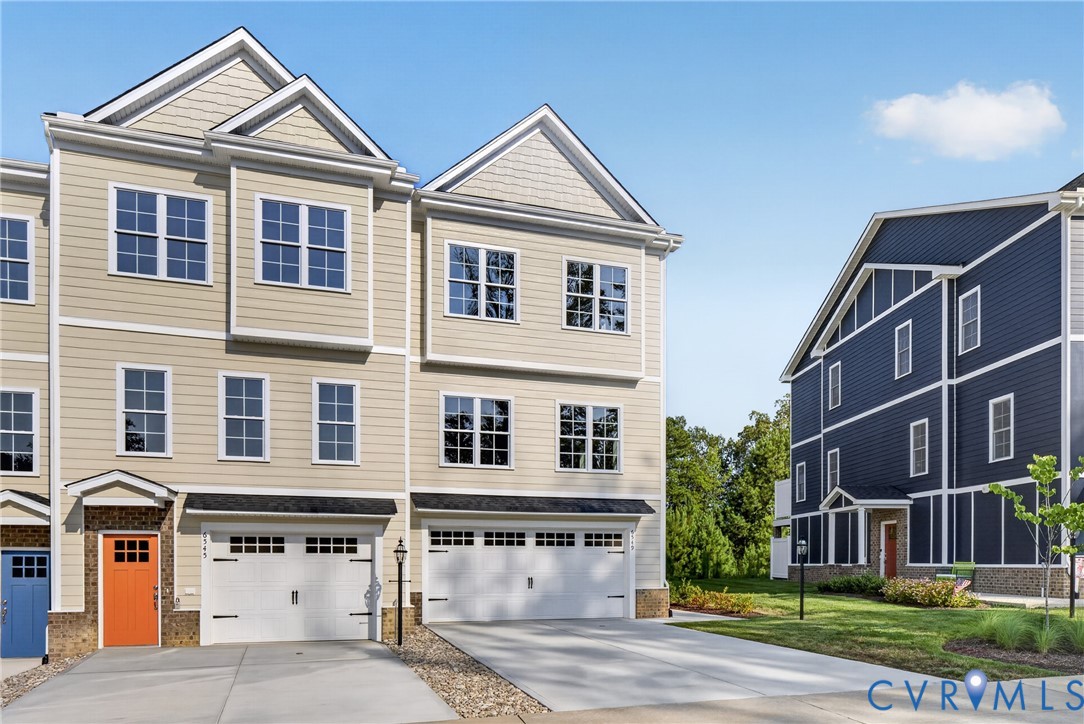 Three-story exterior with light-colored siding, multiple windows, and a two-car garage