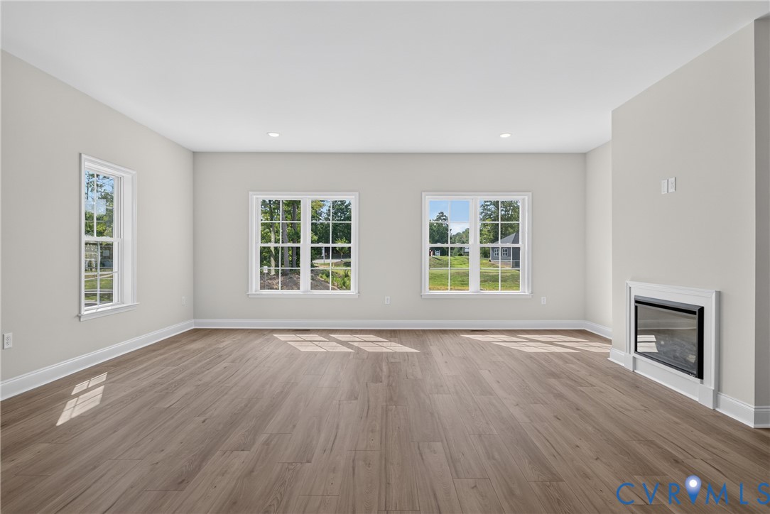 Spacious interior with wood-finish flooring, recessed lighting, multiple windows, and a built-in fireplace feature