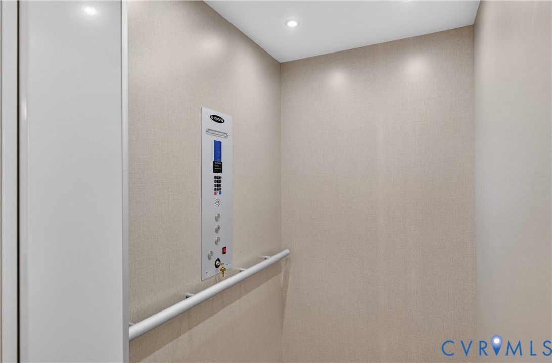 Built-in elevator with neutral wall covering, recessed ceiling lighting, and a grab bar