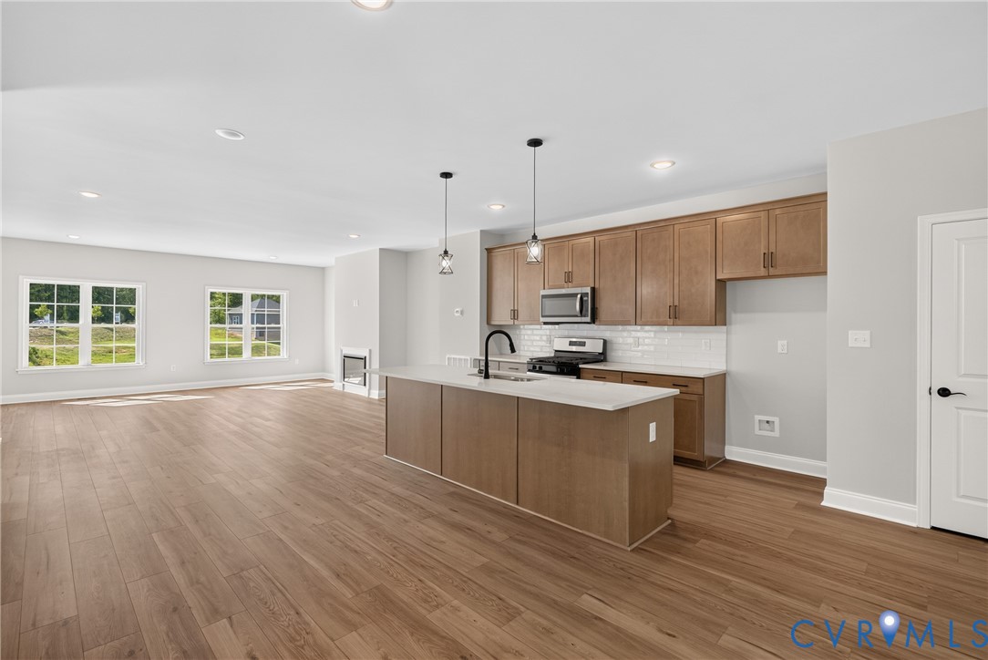 Open-concept kitchen and living area featuring wood-finish flooring, recessed lighting, and ample natural light from multiple windows