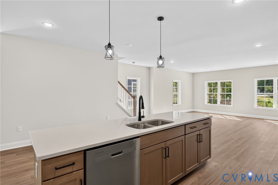 Kitchen island with a light-toned countertop, stainless steel double basin sink, and integrated dishwasher