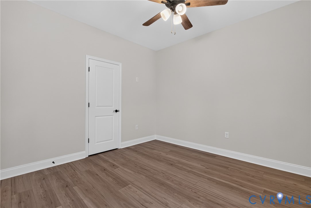 Wood-finish flooring, light gray wall paint, and a ceiling fan with integrated lighting