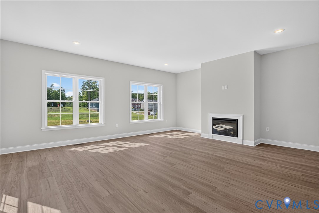 Wood-finish flooring, recessed lighting, and a built-in fireplace with a white mantel and surround