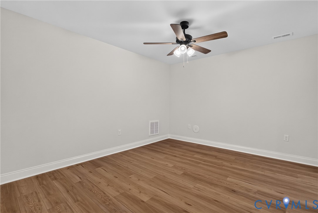 Wood-finish flooring, light gray walls, and a ceiling fan with integrated lighting Wood-finish flooring, light gray walls, and a ceiling fan with integrated lighting