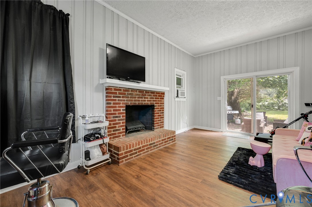 Brick fireplace with a white mantel, wood-finish flooring, and sliding glass doors to the exterior