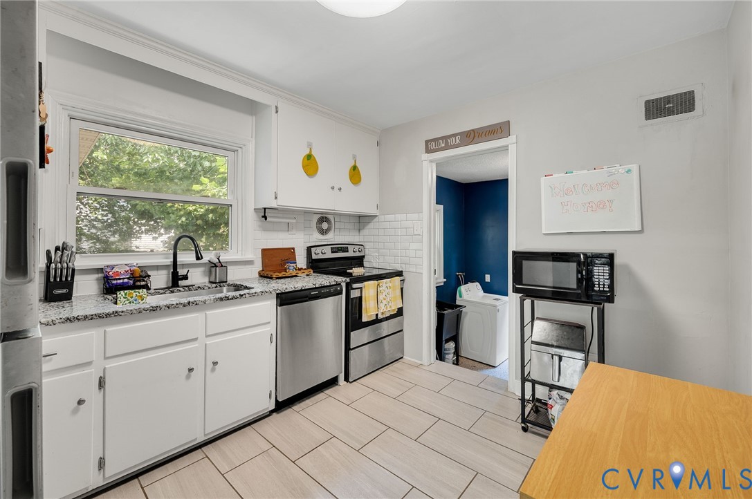 White cabinetry, stone-finish countertops, stainless steel appliances, subway tile backsplash, and light-toned tile flooring