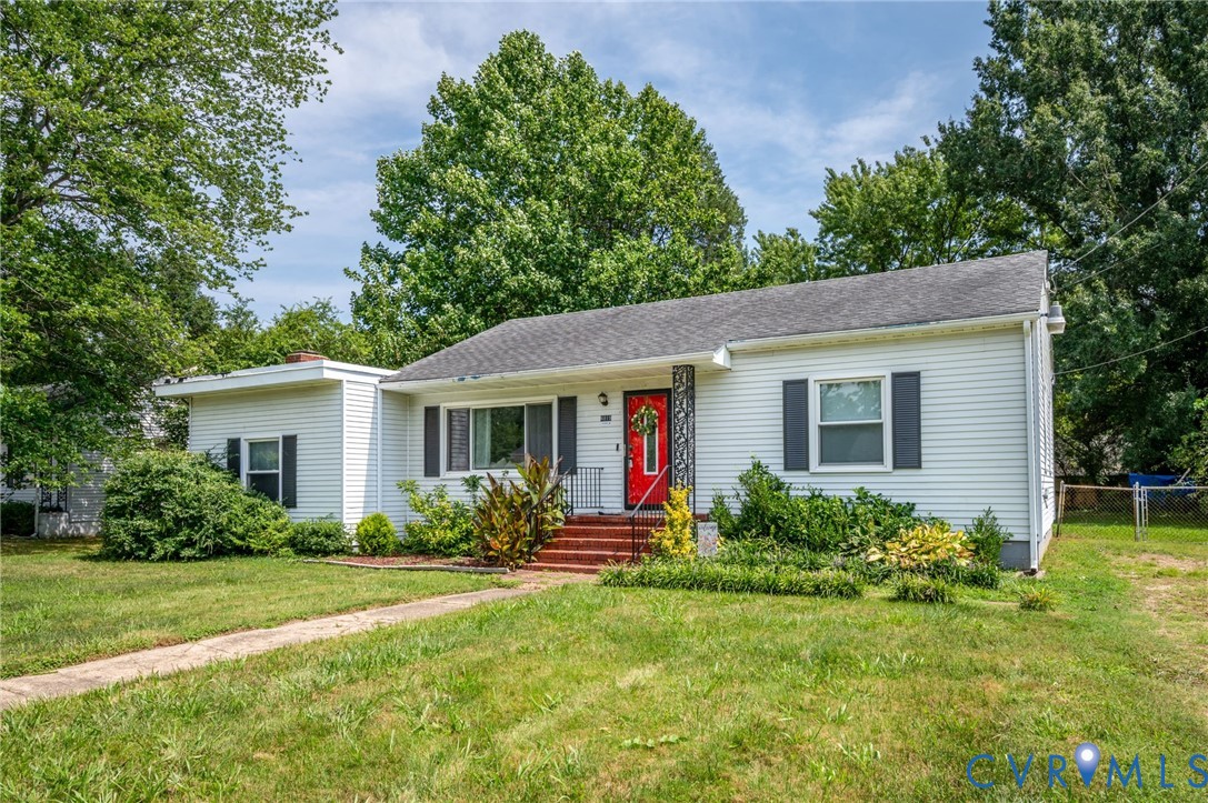 White siding exterior with a red entry door, framed by dark shutters White siding exterior with a red entry door, framed by dark shutters