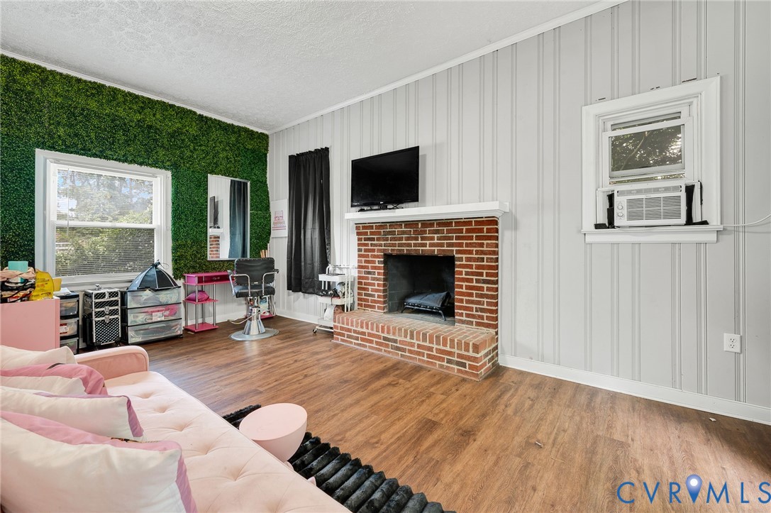 Brick fireplace with a white mantel, wood-finish flooring, and vertical paneling