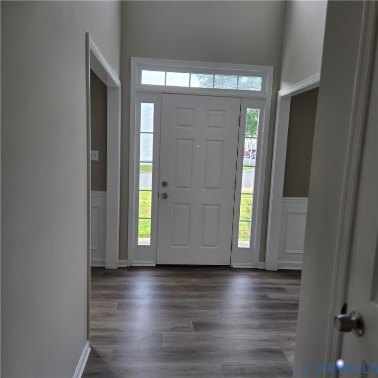 Entryway featuring a paneled door with sidelights and transom window, wood-finish flooring, and wainscoting