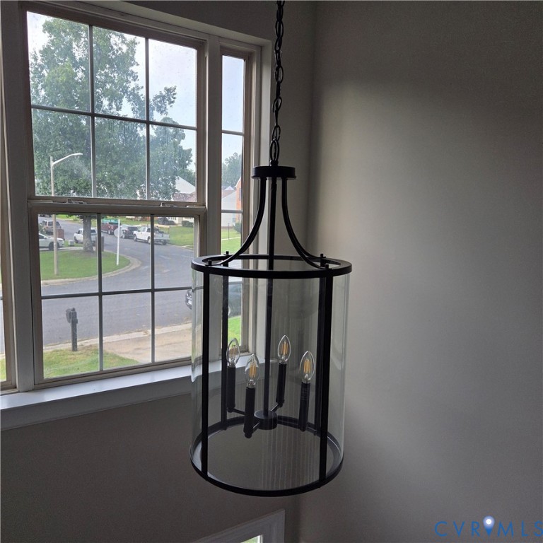 Black metal chandelier with clear glass cylindrical enclosure and four candelabra-style bulbs