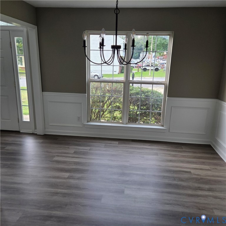 Wood-finish flooring, wainscoting, an overhead chandelier, and a multi-pane window