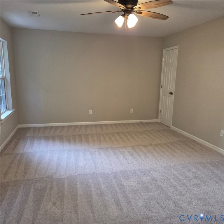 Carpeted flooring, neutral wall tones, window with natural light, ceiling fan with integrated lighting