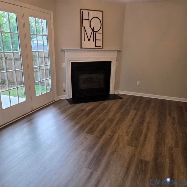 Fireplace with a white mantel, wood-finish flooring, and double French doors opening to a patio