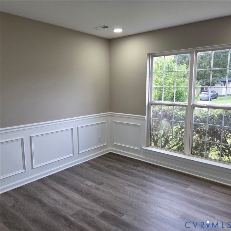 Recessed lighting, wood-finish flooring, accent wall paneling, large multi-pane window, and light-toned wall paint