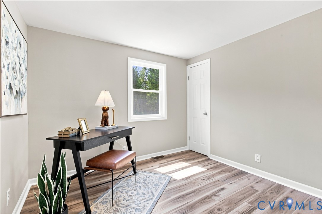 Light gray walls, wood-finish flooring, white trim, and a white window frame