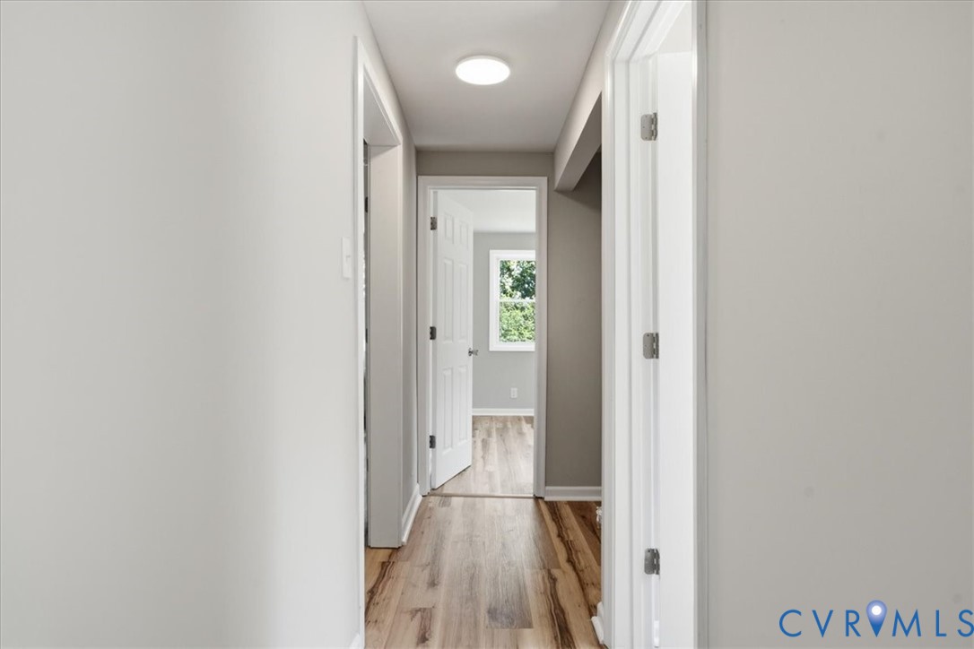 Hallway featuring wood-finish flooring, white trim, and a recessed ceiling light