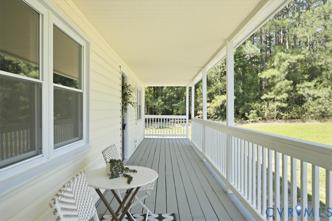 Expansive covered porch featuring a painted wood floor, white railing, and multiple windows with screens
