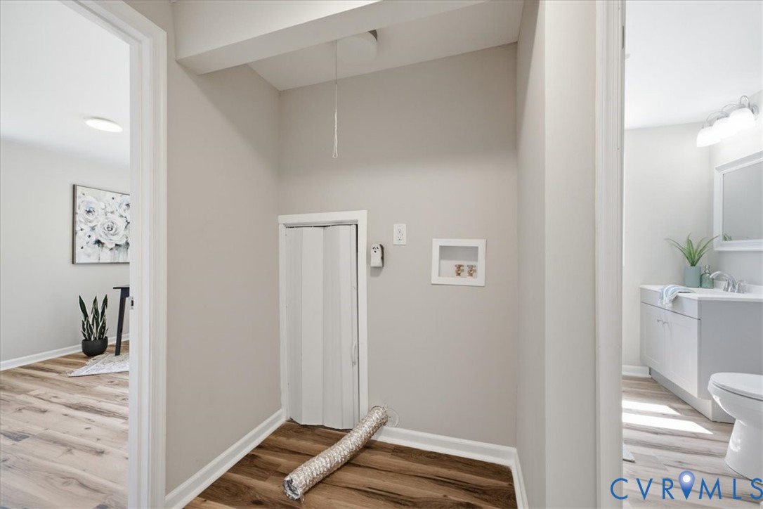 Dedicated laundry area featuring wood-finish flooring and neutral wall tones