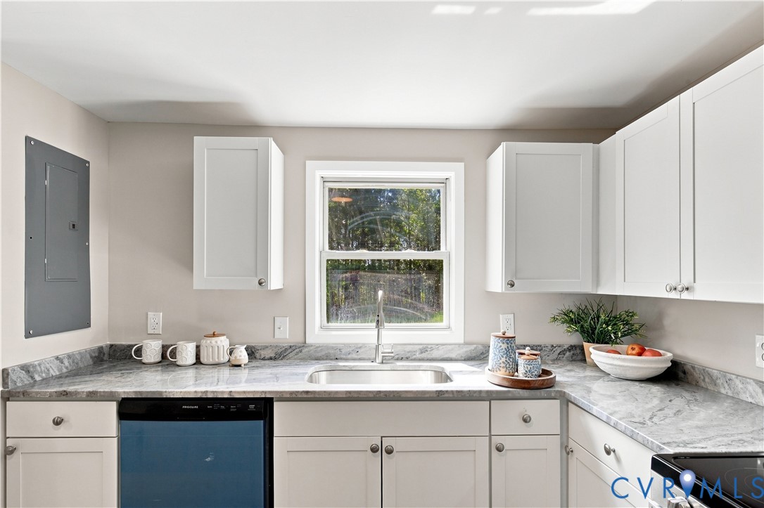 White shaker-style cabinetry, stainless steel sink, built-in dishwasher, and gray patterned countertops