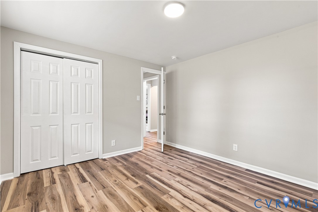 Wood-finish flooring, white bi-fold closet doors, painted walls, and overhead flush-mount lighting
