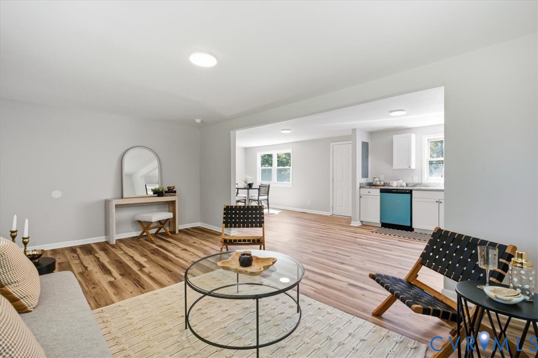 Open-concept living area featuring wood-finish flooring, recessed lighting, and a bright kitchen with white cabinetry and a blue dishwasher
